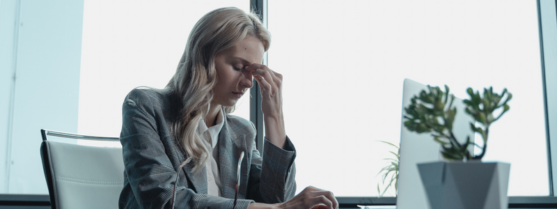 Lady holds her head in her hand at her desk