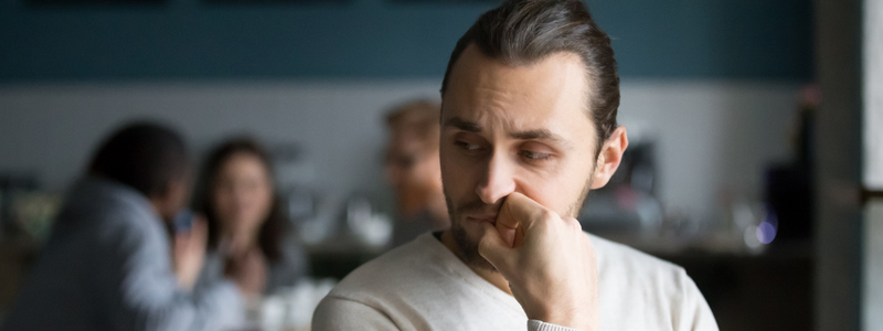 man looks worried as people chat behind him