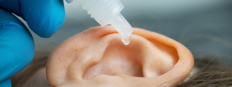 A person has ear drops administered by a professional audiologist